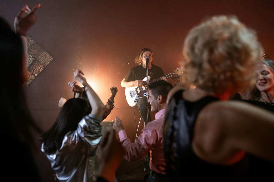 Person on the stage playing electric guitar.