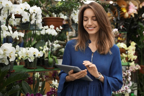 Female florist smiling and working on her iPad in shop