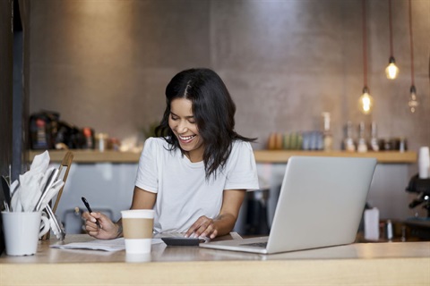 Female sitting a table with her laptop and smiling