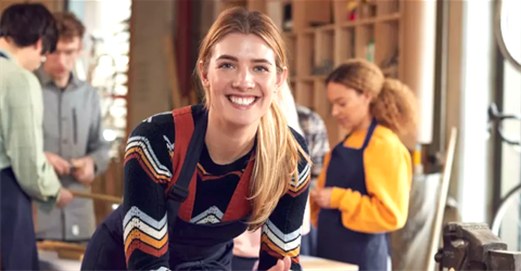 A young lady smiling with some other young people behind her.